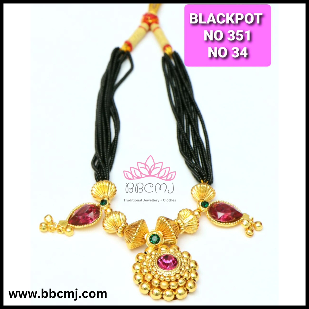 A gold coated kali pot mangalsutra necklace with black beads and red gemstones, accompanied by earrings.